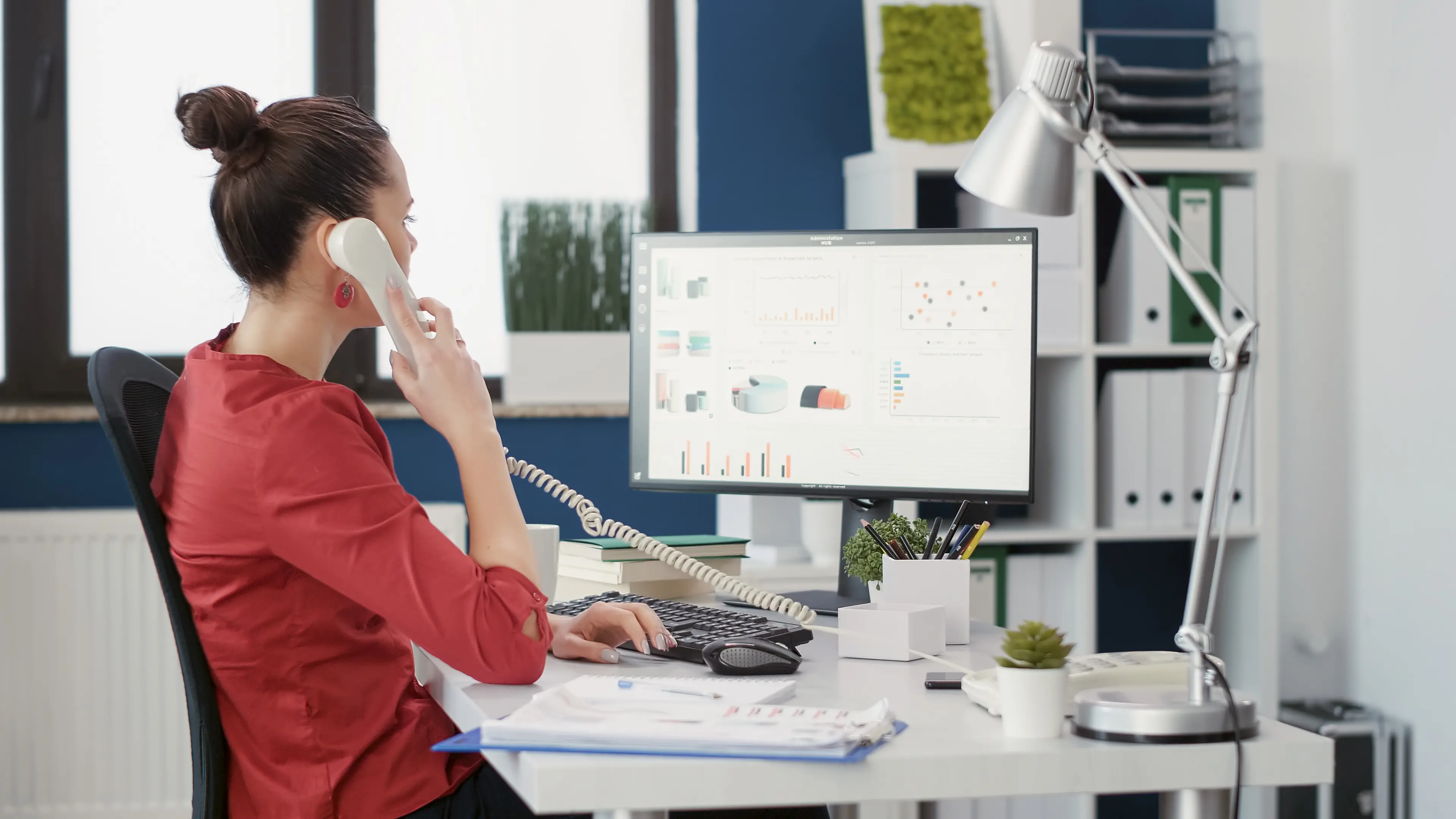 Eine Bürosekretärin verwendet ein Festnetztelefon, um über die Arbeit zu sprechen, und führt ein Ferngespräch, um das Geschäftswachstum voranzutreiben. Eine weibliche Mitarbeiterin nimmt im Büro eines Start-up-Unternehmens einen Telefonanruf entgegen.